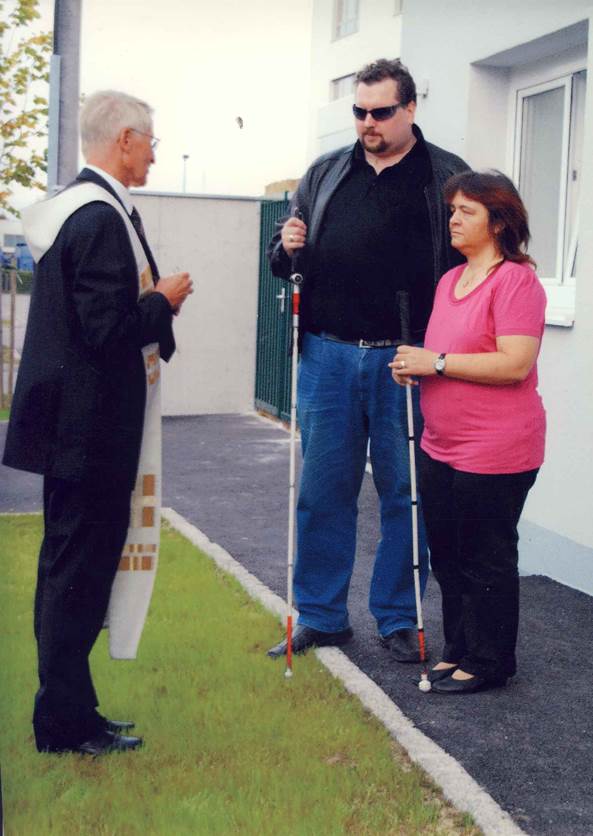 Elfi und Dietmar mit Pfarrer vor ihrem Haus bei der Einweihung 2009